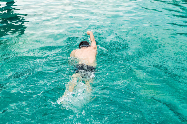 Draufsicht eines jungen kaukasischen Mannes, der in einem Swimmingpool schwimmt - Foto, Bild
