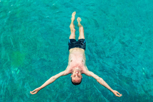 Vue de dessus d'un jeune homme flottant dans une piscine à bras ouverts
 - Photo, image