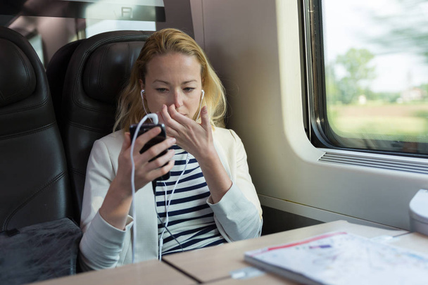 Деловая женщина, общающаяся по мобильному телефону во время поездки на поезде. - Фото, изображение