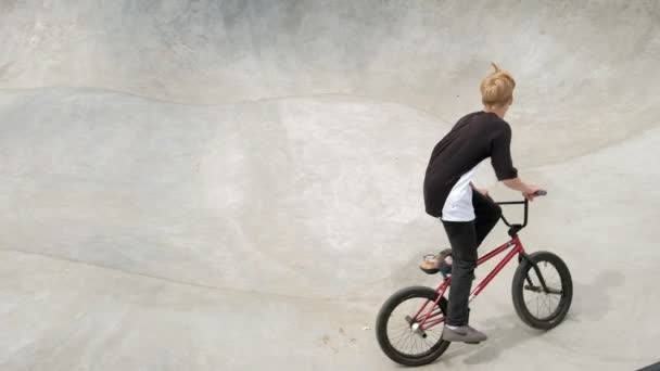 Ein Junge reitet an einem sonnigen Tag in einem Skateboard-Park seine Tricks mit dem Fahrrad. Superzeitlupe - Filmmaterial, Video