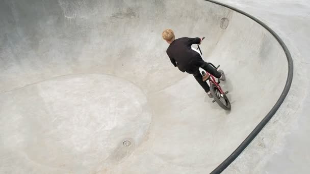 Ein Junge reitet an einem sonnigen Tag in einem Skateboard-Park seine Tricks mit dem Fahrrad. Superzeitlupe - Filmmaterial, Video