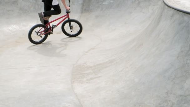Um menino está montando BMX truques de ciclismo em um parque de skate em um dia ensolarado. Movimento super lento
 - Filmagem, Vídeo
