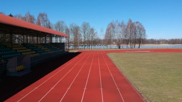 Pista de atletismo con línea y tribuna en pequeño estadio en primavera, vista aérea
 - Metraje, vídeo