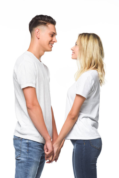side view of couple holding hands and looking at each other isolated on white - Zdjęcie, obraz