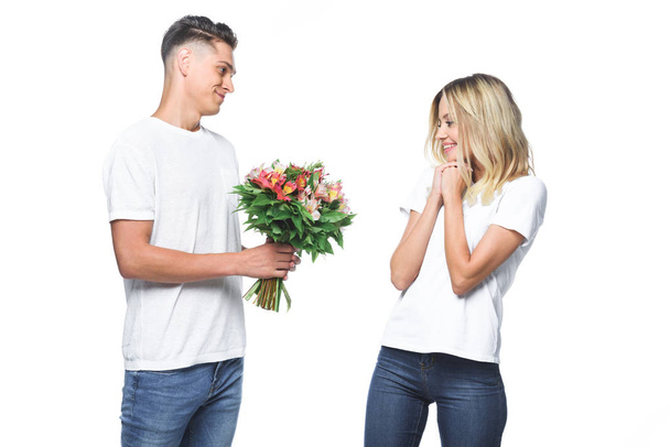 side view of boyfriend presenting bouquet to surprised girlfriend isolated on white - Foto, imagen