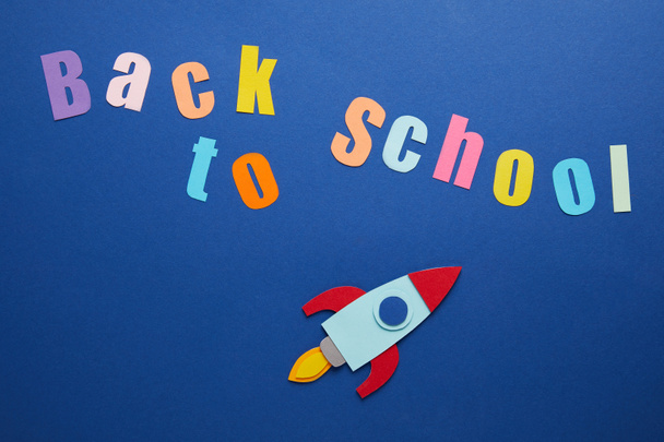 vista superior de las letras de vuelta a la escuela con cohete sobre fondo azul
 - Foto, Imagen