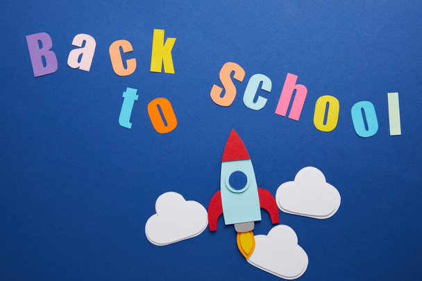 top view of back to school lettering with clouds and rocket on blue background - Photo, Image