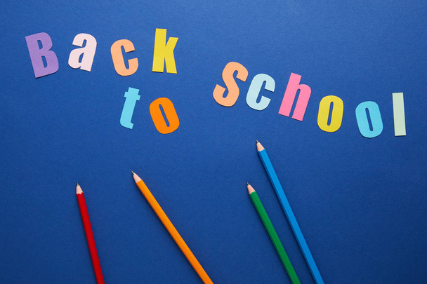 top view of back to school lettering with pencils on blue background - Foto, afbeelding