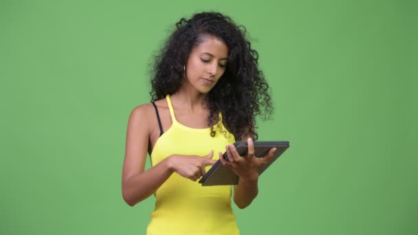 Young beautiful Hispanic woman thinking while using digital tablet - Felvétel, videó