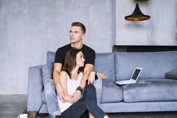 pretty woman and a man watch a laptop on the sofa together - Foto, Imagen