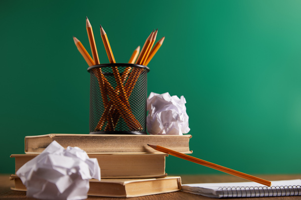 books, crumpled papers and pencils with green chalkboard on background - Photo, Image