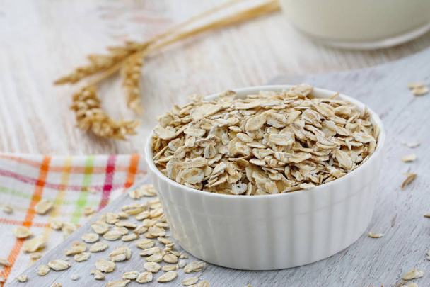 Oat flakes in a glass bowl and jug of milk for healthy breakfast - Photo, Image