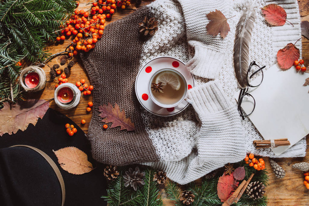 Stylish Flat lay view of autumn leaves and tartan textured sweater on wooden background with cup of tea .  Autumn or Winter concept.  - Zdjęcie, obraz