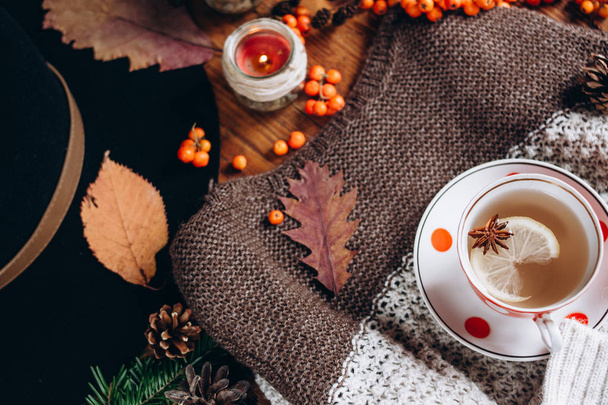 Stylish Flat lay view of autumn leaves and  textured sweater on wooden background with cup of tea .  Autumn or Winter concept. - Foto, immagini