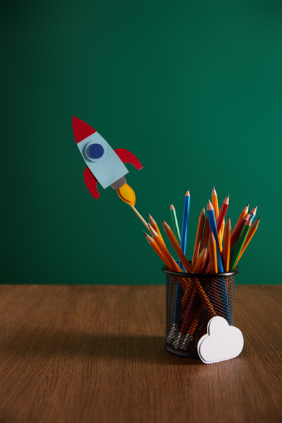 crayons colorés, fusée, panneau nuage sur table en bois avec tableau noir sur fond
 - Photo, image