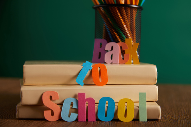 back to school lettering with pencils and books on table - Foto, afbeelding