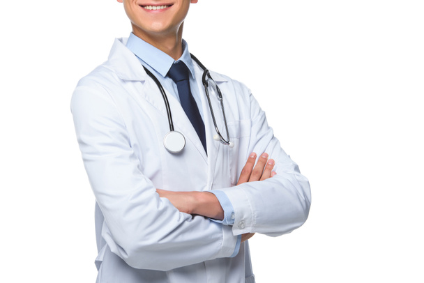 oříznuté záběr usměvavý mladý doktor s překřížením rukou izolované na bílém - Fotografie, Obrázek