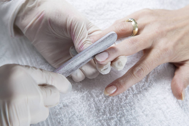 Nail Treatment - Manicurist Filing Fingernails With Nail File, Making A Perfect Nail Form On White Towel Closeup - Foto, imagen