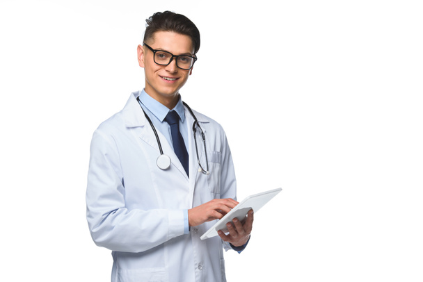 handsome young doctor using tablet and looking at camera isolated on white - Photo, image