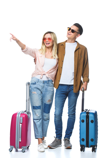 young travelling couple with suitcases pointing somewhere isolated on white - Foto, afbeelding