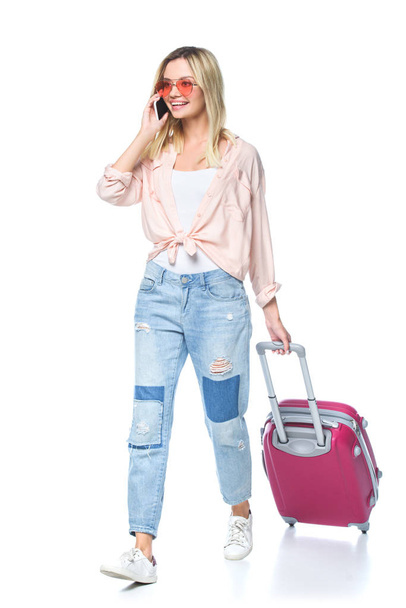 joven viajera con equipaje hablando por teléfono y caminando aislada en blanco
 - Foto, imagen