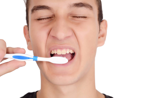 Close up of young man brushing his teeth. Health and beauty concept. Isolated white background - 写真・画像