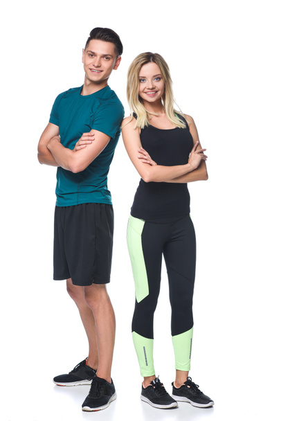 young fit couple with crossed arms looking at camera isolated on white - Photo, Image