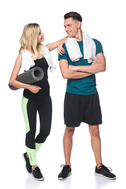 jovem casal desportivo com toalhas nos ombros e tapete de ioga isolado no branco
 - Foto, Imagem