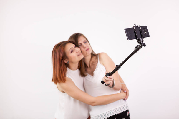 Porträt zweier schöner junger Frauen, die ein Selfie mit einem Selfie-Stick machen - Foto, Bild