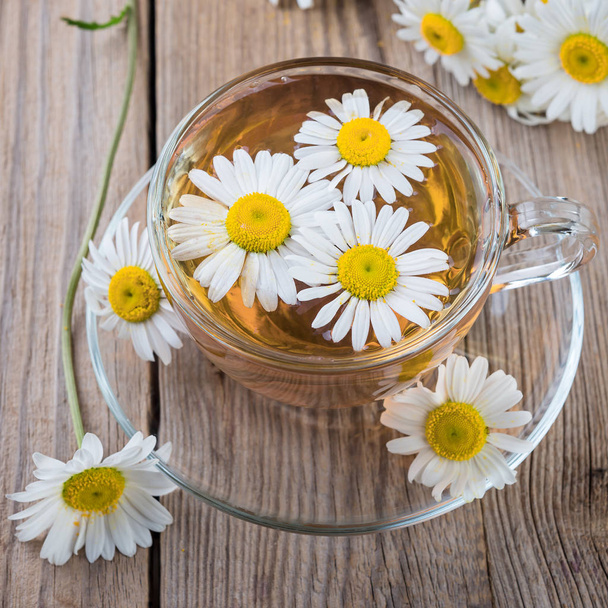 taza de té de manzanilla y flores de manzanilla sobre fondo de madera
 - Foto, imagen