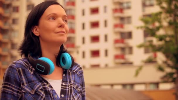 Brünette Frau trägt blaue Kopfhörer in modernem Viertel - Filmmaterial, Video