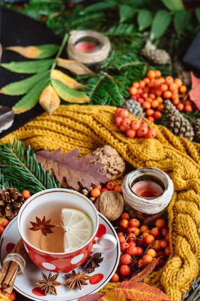  Flat lay view of autumn leaves,candles  and textured scarf on wooden background with cup of tea . Autumn or Winter concept. - Фото, зображення