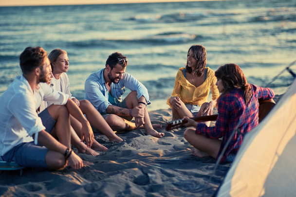 Grup Genç arkadaşlar eğlenmeye sahilde gitar ile gülümseyen - Fotoğraf, Görsel