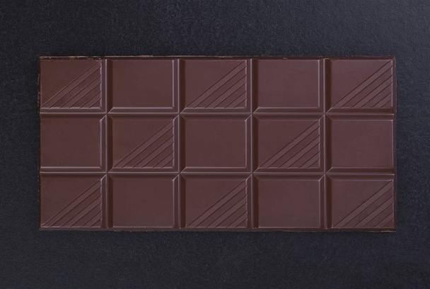 Milk chocolate bar on a black background closeup - Фото, изображение