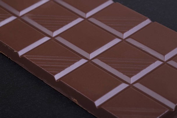 Milk chocolate bar on a black background closeup - Fotoğraf, Görsel
