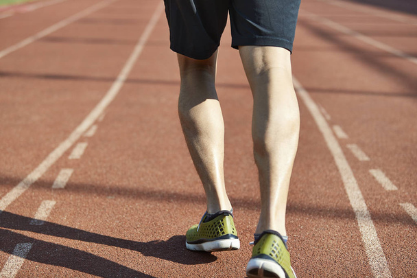 Nahaufnahme der Beine eines männlichen Athleten, der bereit ist, auf der Strecke zu laufen. - Foto, Bild