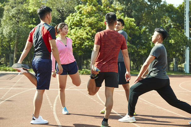 vier Aziatische jonge volwassenen warming-up benen strekken op de rails. - Foto, afbeelding