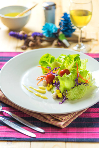 Afbeelding van verse gezonde salade en glas witte wijn op houten tafel. (verticaal)) - Foto, afbeelding