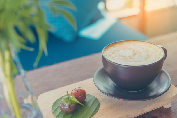 Vintage tón obrazu Latte káva umění v hnědé cup na dřevěný stůl. - Fotografie, Obrázek