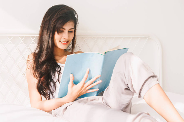 Donna che legge libro sul letto al mattino
 - Foto, immagini