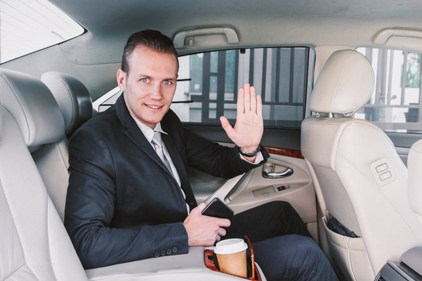 Handsome businessman in suit sitting on back seat of a car - Photo, Image