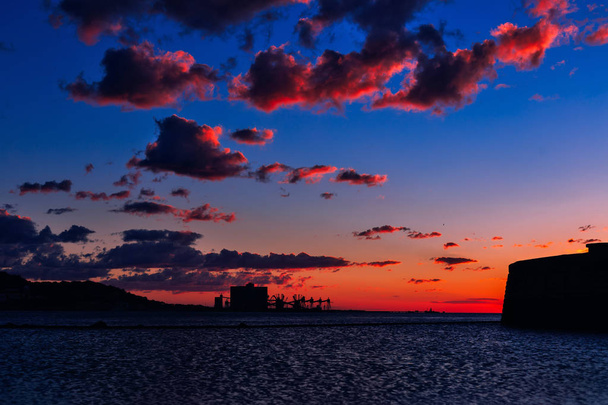 日没からピンクの色合いとさまざまな形の雲。テージョ川の展望デッキでの人々 は、夕日を眺める - 写真・画像