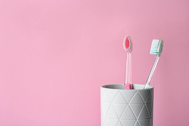 Tasse mit Zahnbürsten vor farbigem Hintergrund - Foto, Bild
