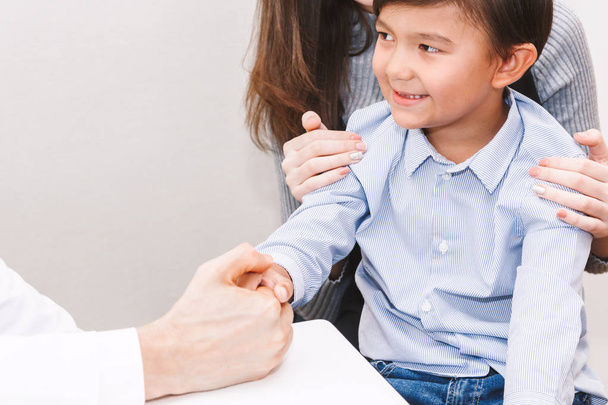Κρατώντας το χέρι γιατρός μικρό αγόρι με φροντίδα στο τραπέζι τους γιατρούς στην hospital.healthcare και την ιατρική - Φωτογραφία, εικόνα