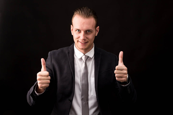 Businessman with thumb up isolated on black background - Photo, Image
