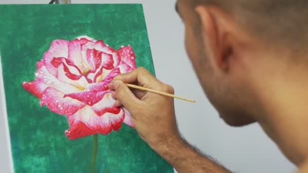 Aziatische kunstenaar schilderen rode roos bloem op groene achtergrond met acryl kleur op doek. - Video