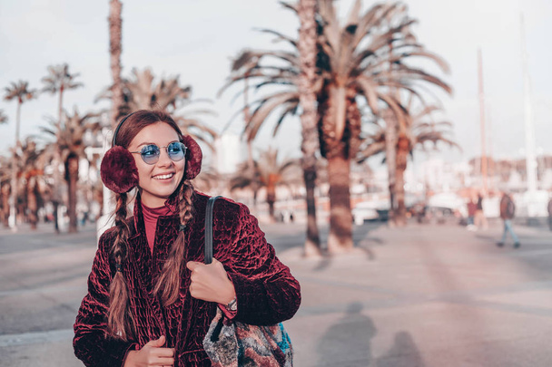 Happy woman in sunglasses and dress walking outdoors. Looking at camera.Sunny lifestyle fashion portrait of young stylish hipster woman walking on the street, wearing trendy outfit,leather coat, bag. - Foto, afbeelding