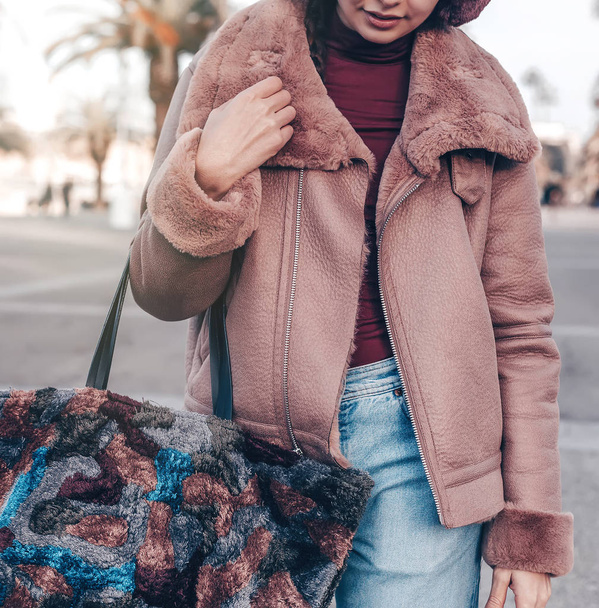 jeune belle femme élégante marchant dans la rue, vêtue d'un manteau rose, tenant un sac coloré, jeans, tenue de mode, tendance automnale, accessoires, mains gros plan, détails
. - Photo, image