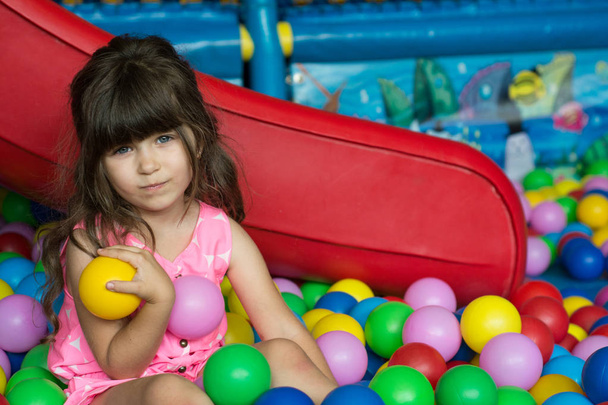 Child playing with colorful balls at playground ball pool. Activity toys for little kid - Foto, Imagen