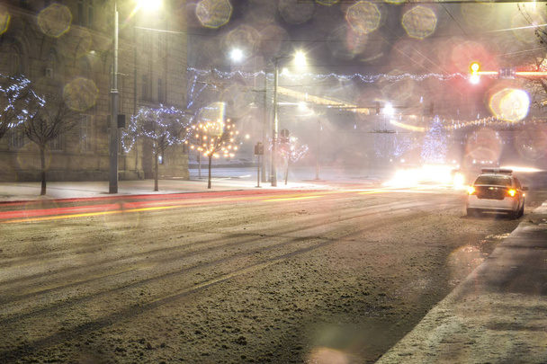 αυτοκίνητο της αστυνομίας στη μέση ένα ολισθηρό χιονισμένο δρόμο τη νύχτα - Φωτογραφία, εικόνα